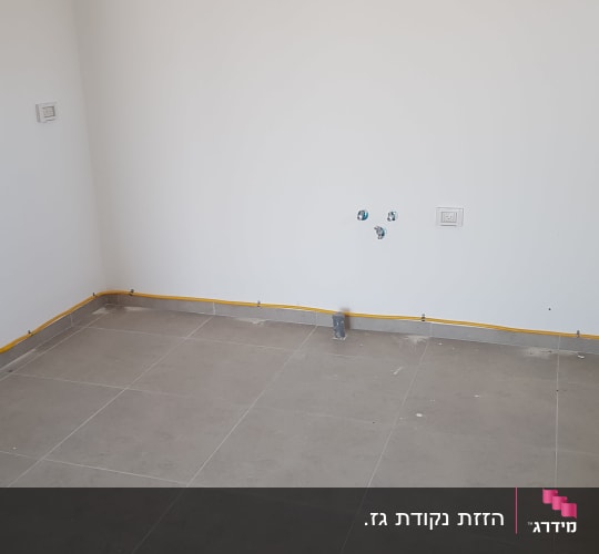 צינור גז צהוב מותקן לאורך הקיר בחדר ריק